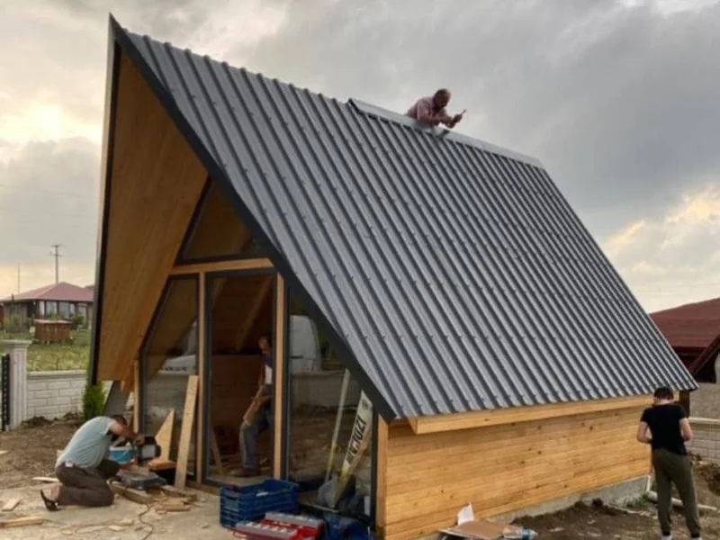 Chalé A-frame moderno com fachada de vidro iluminada na floresta